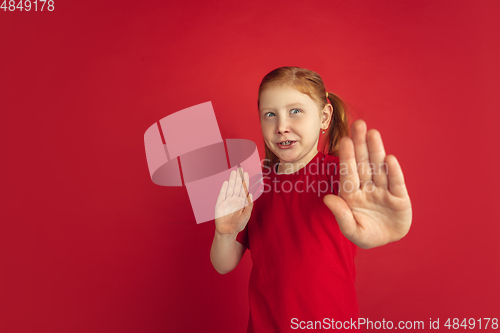 Image of Caucasian little girl portrait isolated on red studio background, emotions concept