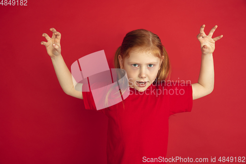 Image of Caucasian little girl portrait isolated on red studio background, emotions concept