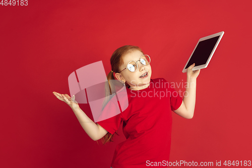 Image of Caucasian little girl portrait isolated on red studio background, emotions concept