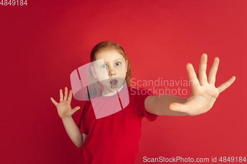 Image of Caucasian little girl portrait isolated on red studio background, emotions concept