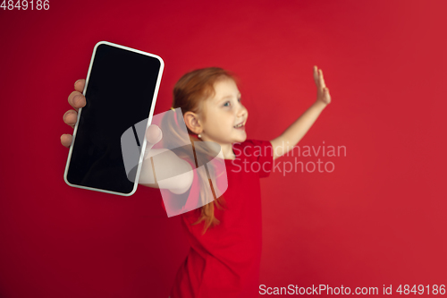 Image of Caucasian little girl portrait isolated on red studio background, emotions concept