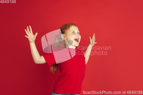 Image of Caucasian little girl portrait isolated on red studio background, emotions concept