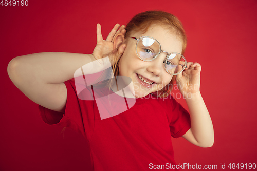 Image of Caucasian little girl portrait isolated on red studio background, emotions concept