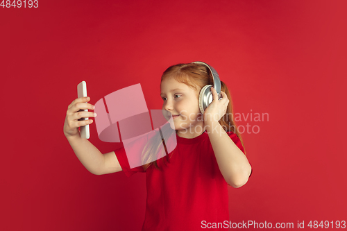 Image of Caucasian little girl portrait isolated on red studio background, emotions concept