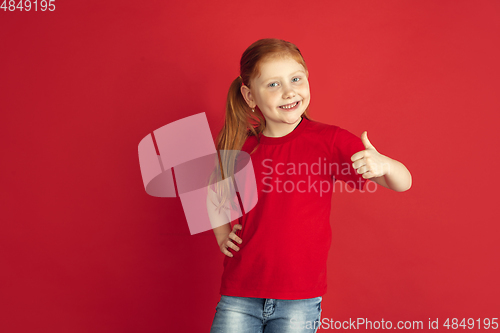 Image of Caucasian little girl portrait isolated on red studio background, emotions concept