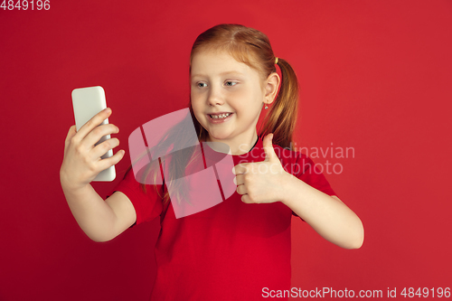 Image of Caucasian little girl portrait isolated on red studio background, emotions concept