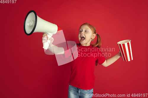 Image of Caucasian little girl portrait isolated on red studio background, emotions concept