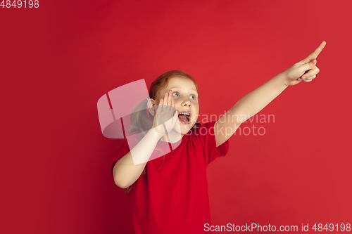 Image of Caucasian little girl portrait isolated on red studio background, emotions concept