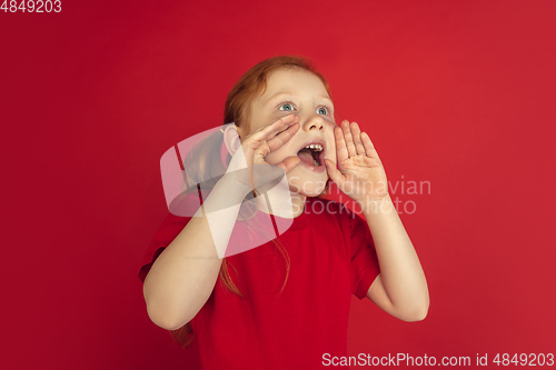 Image of Caucasian little girl portrait isolated on red studio background, emotions concept