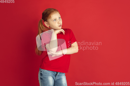 Image of Caucasian little girl portrait isolated on red studio background, emotions concept