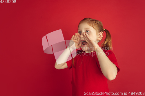 Image of Caucasian little girl portrait isolated on red studio background, emotions concept