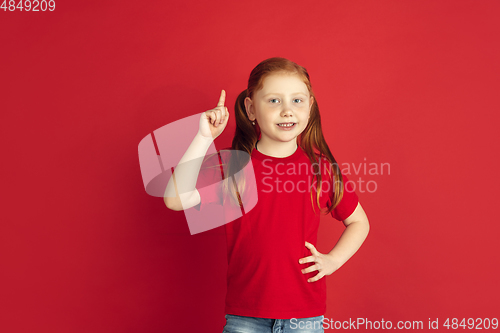 Image of Caucasian little girl portrait isolated on red studio background, emotions concept