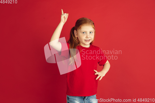 Image of Caucasian little girl portrait isolated on red studio background, emotions concept