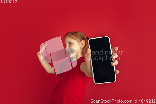 Image of Caucasian little girl portrait isolated on red studio background, emotions concept