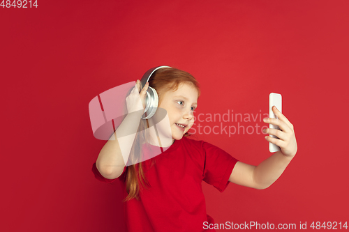 Image of Caucasian little girl portrait isolated on red studio background, emotions concept