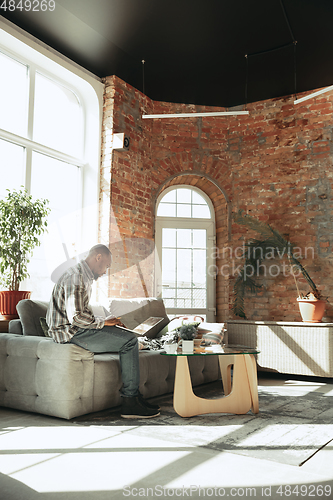 Image of African-american man, freelancer during the work in home office while quarantine