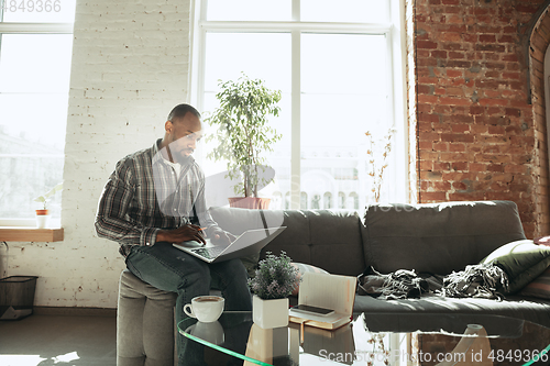 Image of African-american man, freelancer during the work in home office while quarantine