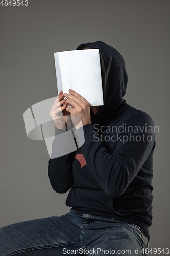 Image of Happy world book day, read to become someone else - man covering face with book while reading on grey background