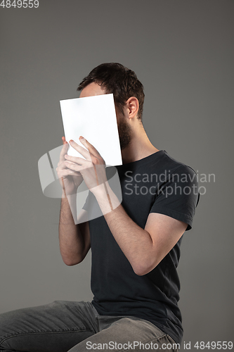 Image of Happy world book day, read to become someone else - man covering face with book while reading on grey background