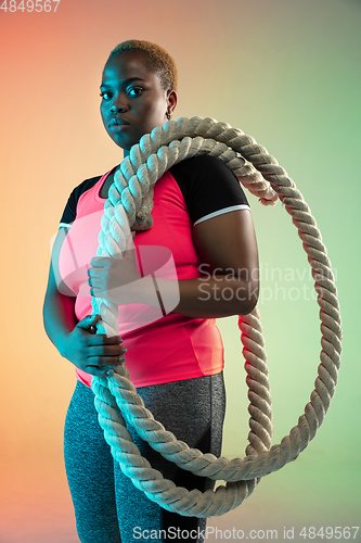 Image of Young african-american plus size female model\'s training on gradient background