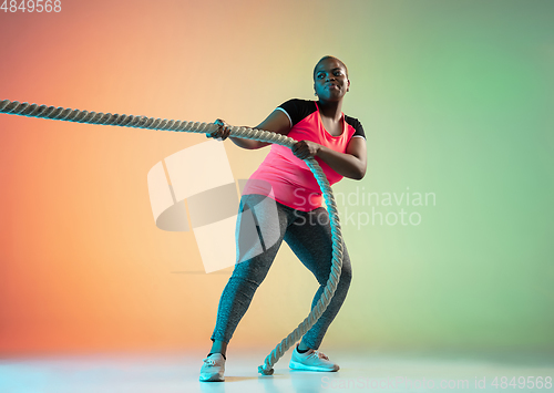 Image of Young african-american plus size female model\'s training on gradient background