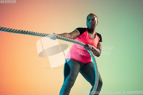 Image of Young african-american plus size female model\'s training on gradient background