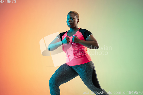 Image of Young african-american plus size female model\'s training on gradient background