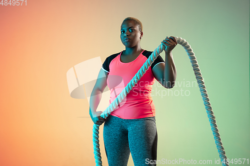 Image of Young african-american plus size female model\'s training on gradient background