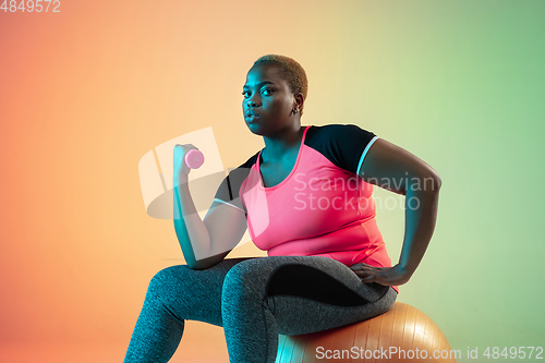 Image of Young african-american plus size female model\'s training on gradient background