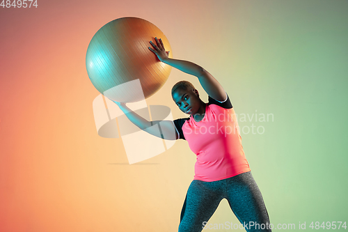 Image of Young african-american plus size female model\'s training on gradient background