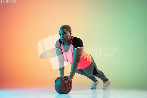 Image of Young african-american plus size female model\'s training on gradient background