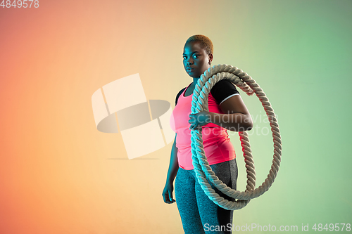 Image of Young african-american plus size female model\'s training on gradient background