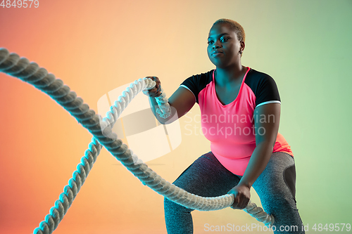 Image of Young african-american plus size female model\'s training on gradient background