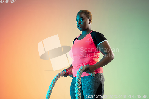 Image of Young african-american plus size female model\'s training on gradient background