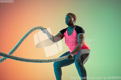 Image of Young african-american plus size female model\'s training on gradient background