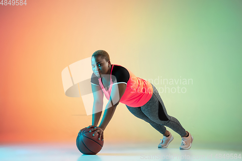Image of Young african-american plus size female model\'s training on gradient background