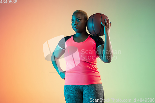 Image of Young african-american plus size female model\'s training on gradient background