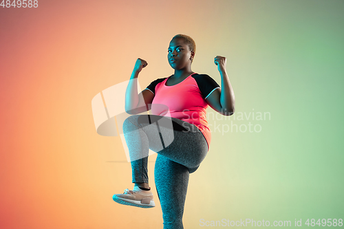 Image of Young african-american plus size female model\'s training on gradient background