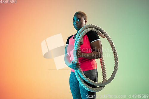 Image of Young african-american plus size female model\'s training on gradient background