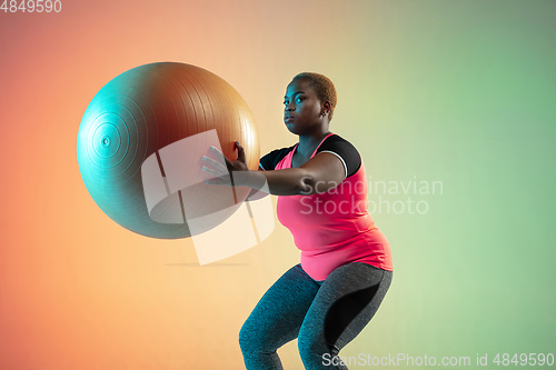 Image of Young african-american plus size female model\'s training on gradient background