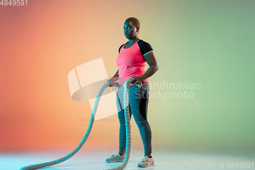 Image of Young african-american plus size female model\'s training on gradient background