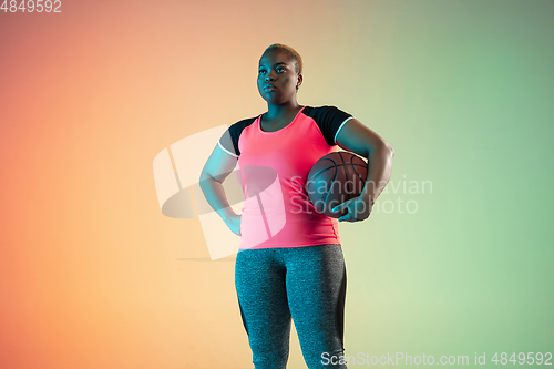 Image of Young african-american plus size female model\'s training on gradient background