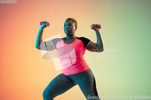 Image of Young african-american plus size female model\'s training on gradient background
