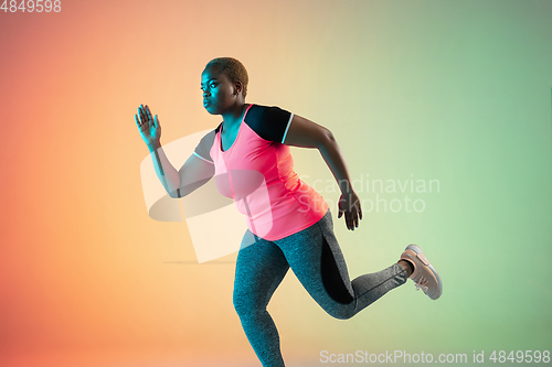 Image of Young african-american plus size female model\'s training on gradient background