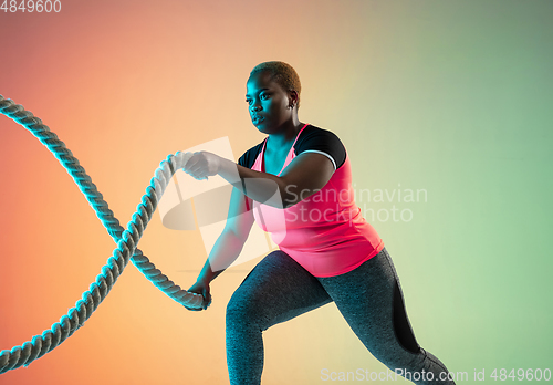 Image of Young african-american plus size female model\'s training on gradient background