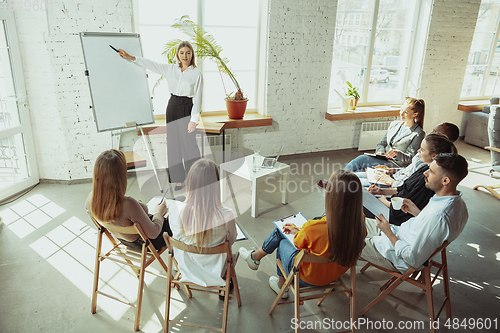 Image of Female caucasian speaker giving presentation in hall at university or business centre workshop