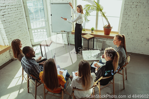 Image of Female caucasian speaker giving presentation in hall at university or business centre workshop