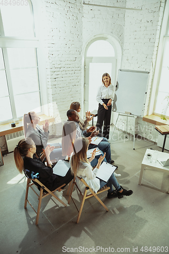 Image of Female caucasian speaker giving presentation in hall at university or business centre workshop