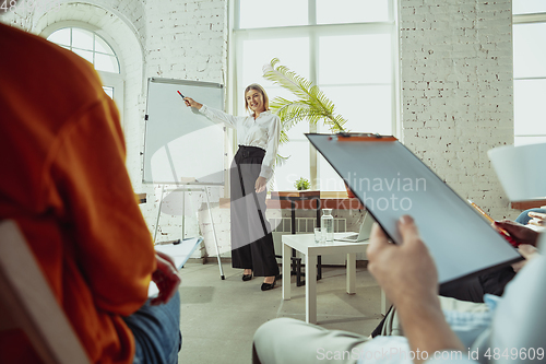 Image of Female caucasian speaker giving presentation in hall at university or business centre workshop