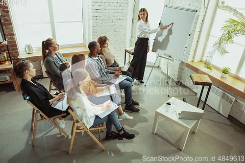 Image of Female caucasian speaker giving presentation in hall at university or business centre workshop
